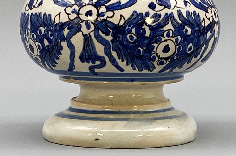 An 18th-century Italian majolica albarello pharmacy jar featuring a waisted silhouette with hand-painted blue floral patterns and central apothecary inscription. View XI