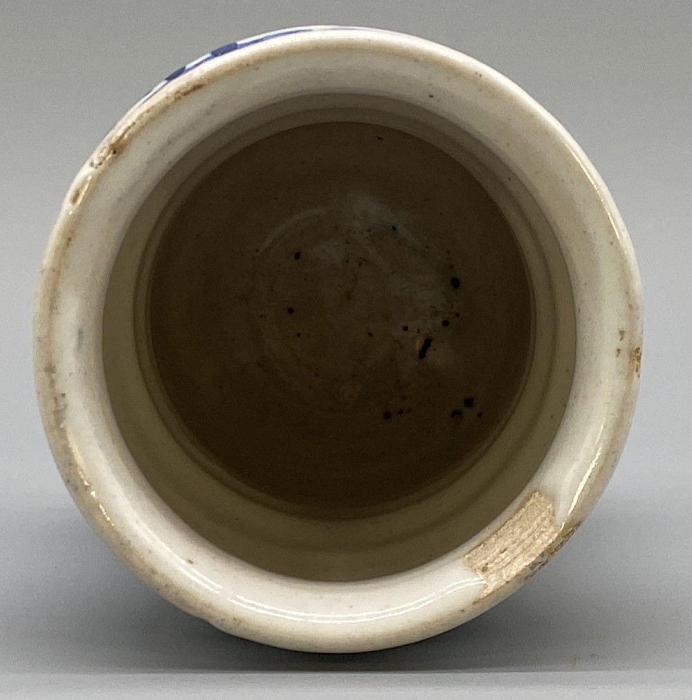 A cylindrical tin-glazed earthenware albarello jar with a waisted body featuring hand-painted blue scrollwork and the date 1709 on a cream-white background. View XII