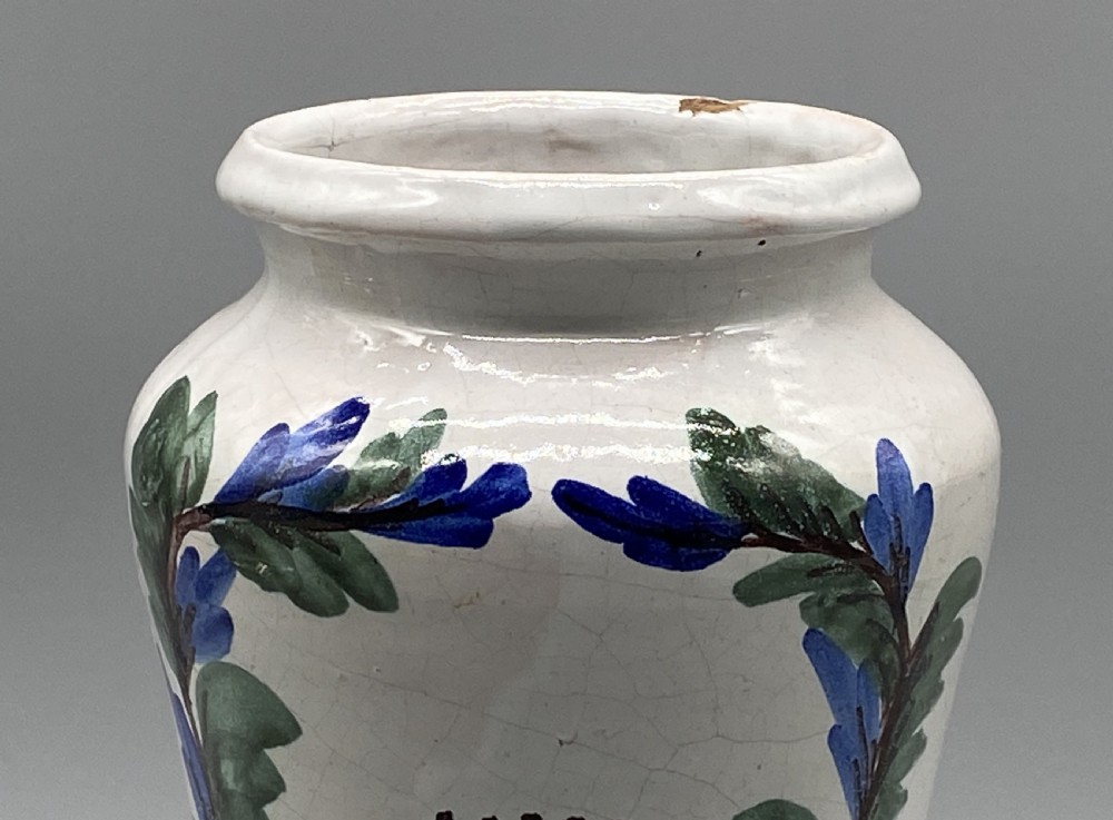 A pair of white tin-glazed ceramic albarello apothecary jars featuring hand-painted green foliage wreaths and Latin script on pedestal bases. View VIII