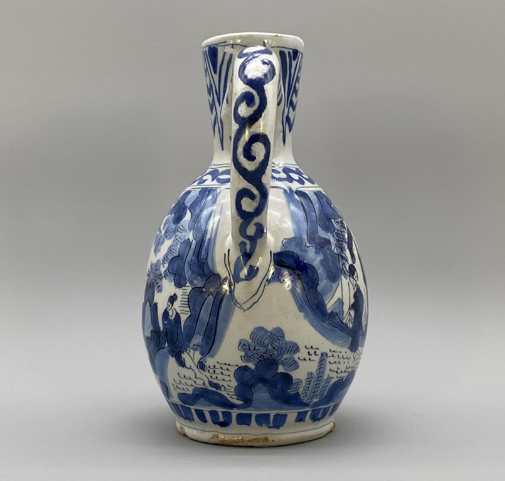 A 17th-century Dutch Delftware ceramic jug featuring hand-painted blue chinoiserie scenes on an opaque white tin glaze with a curved handle. View VII