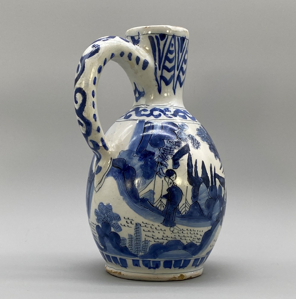A 17th-century Dutch Delftware ceramic jug featuring hand-painted blue chinoiserie scenes on an opaque white tin glaze with a curved handle. View VIII