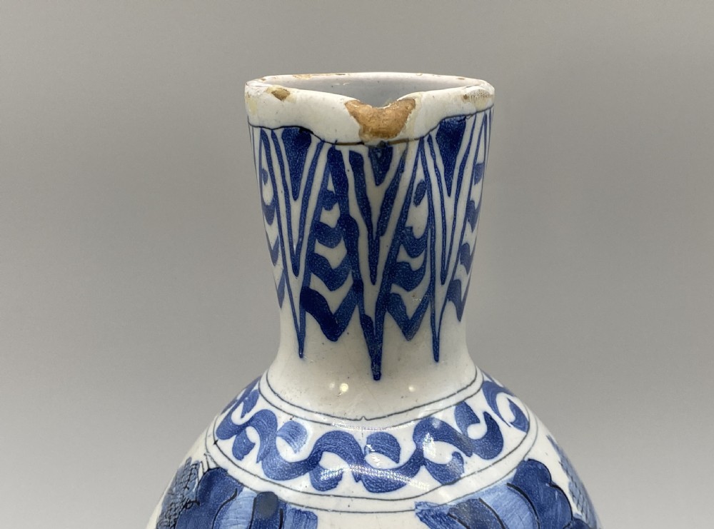 A 17th-century Dutch Delftware ceramic jug featuring hand-painted blue chinoiserie scenes on an opaque white tin glaze with a curved handle. View XI