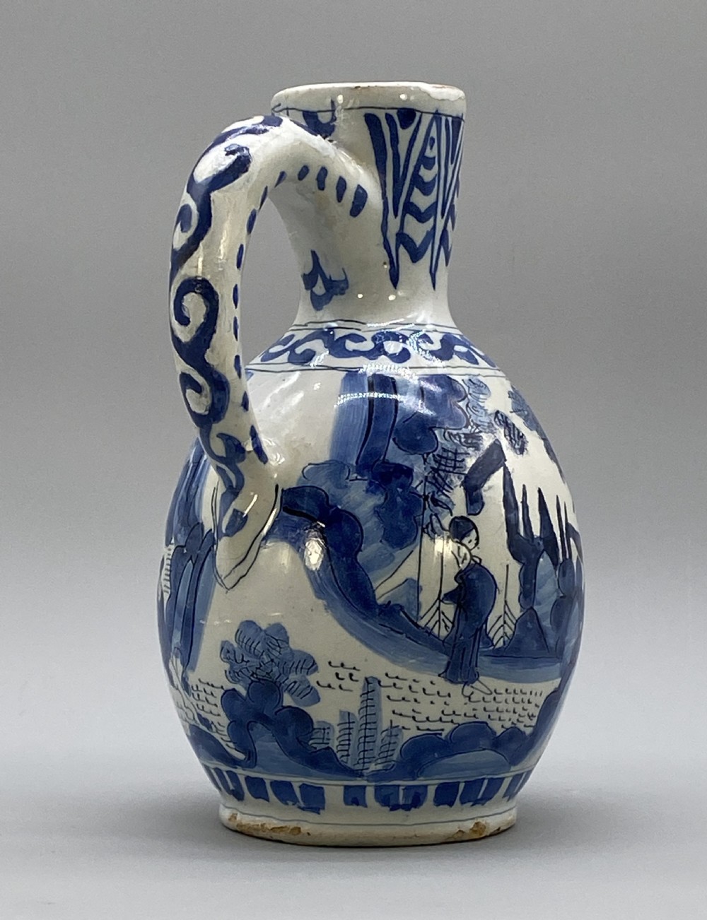 A 17th-century Dutch Delftware ceramic jug featuring hand-painted blue chinoiserie scenes on an opaque white tin glaze with a curved handle. View XVI
