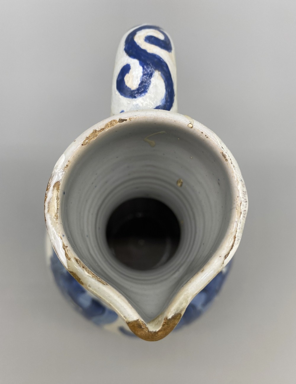 A 17th-century Dutch Delftware ceramic jug featuring hand-painted blue chinoiserie scenes on an opaque white tin glaze with a curved handle. View XVII