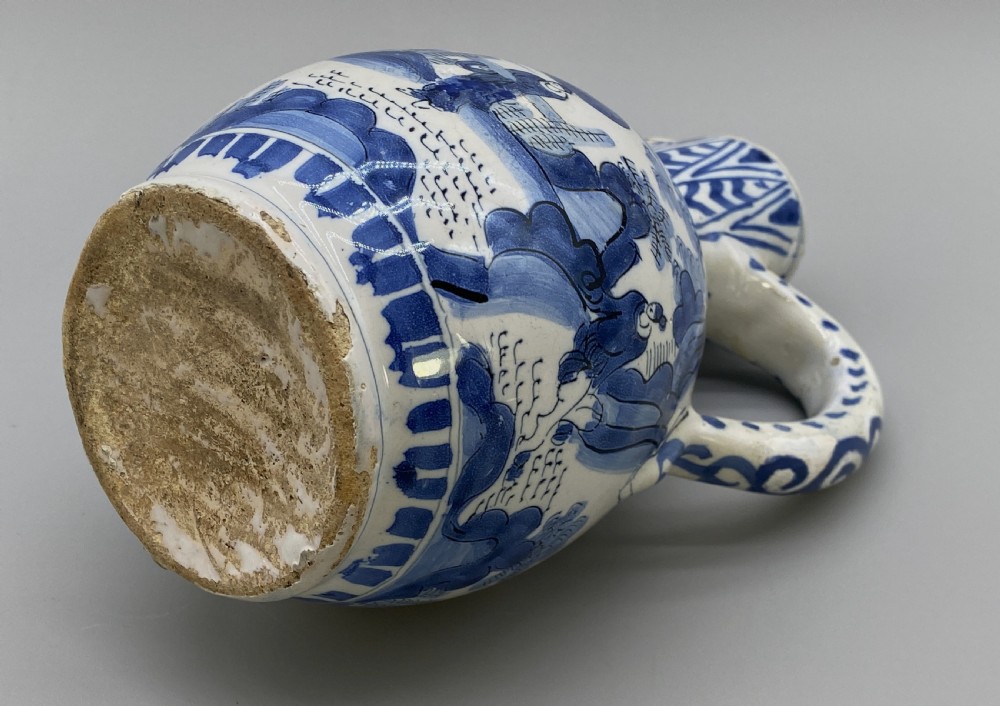 A 17th-century Dutch Delftware ceramic jug featuring hand-painted blue chinoiserie scenes on an opaque white tin glaze with a curved handle. View XVIII