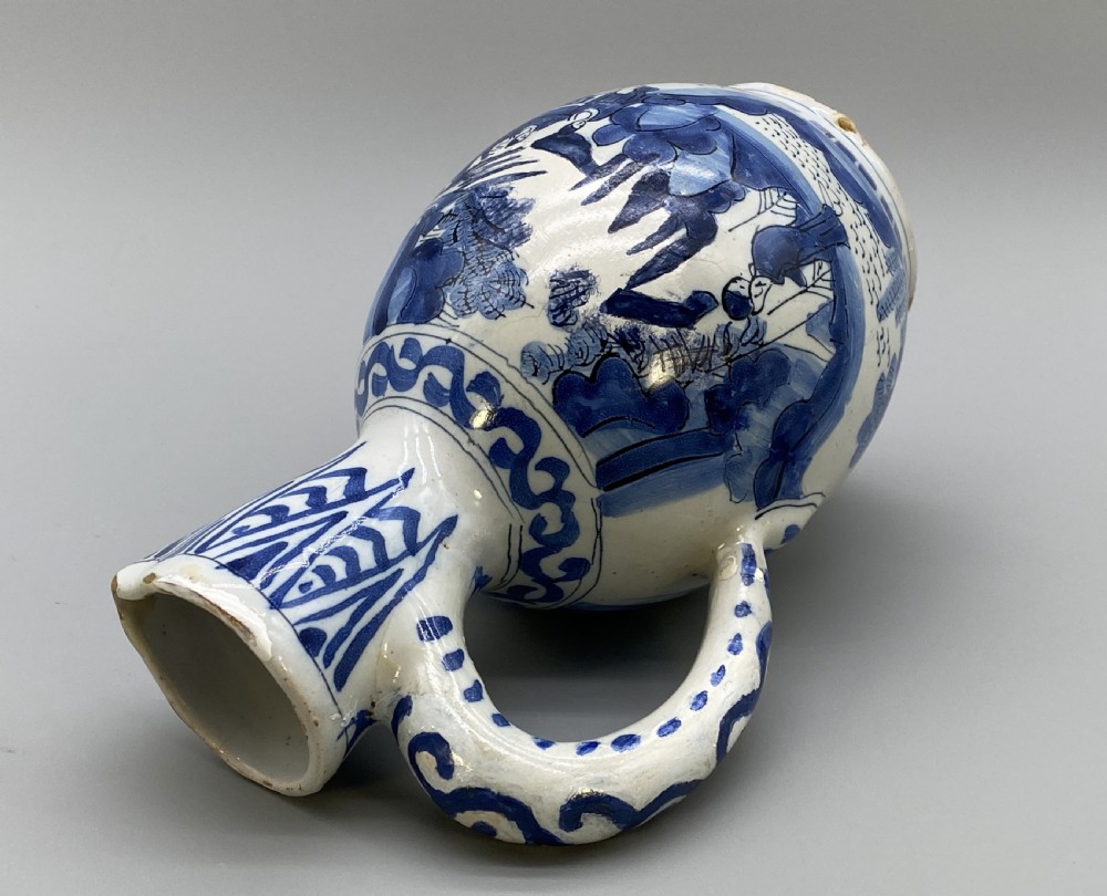 A 17th-century Dutch Delftware ceramic jug featuring hand-painted blue chinoiserie scenes on an opaque white tin glaze with a curved handle. View XIX