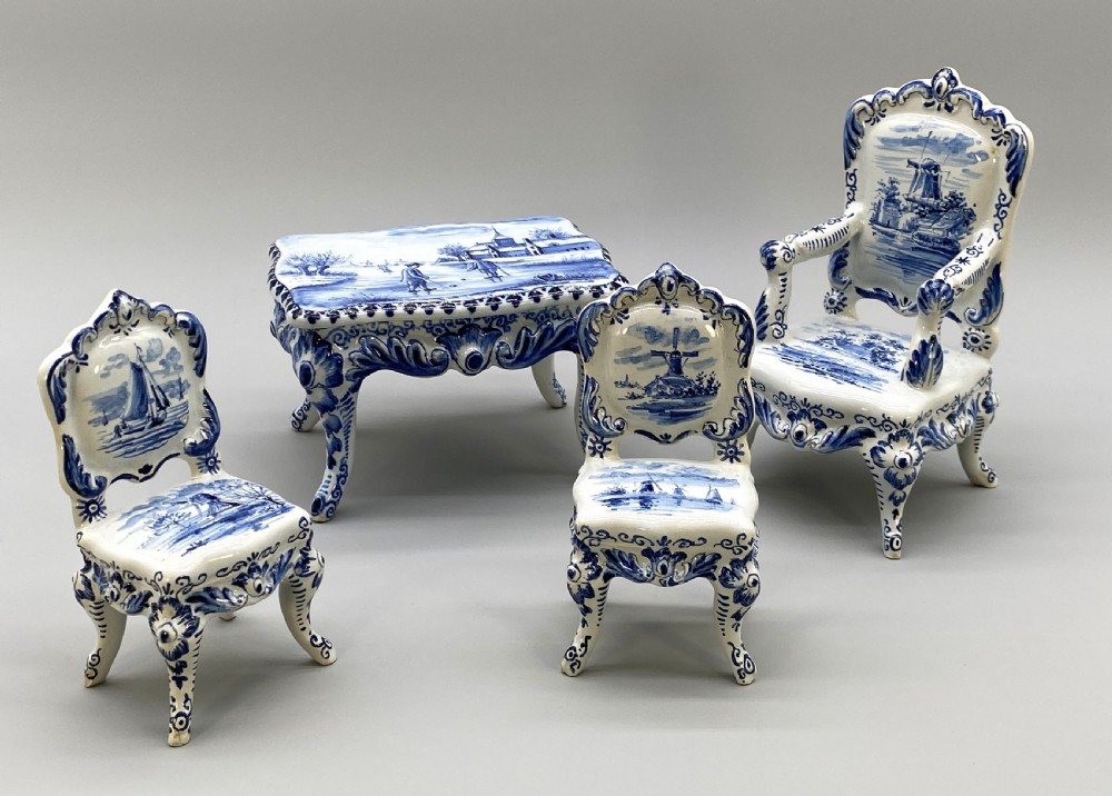 A four-piece set of miniature ceramic furniture decorated with hand-painted blue and white Dutch landscapes and windmill scenes.
