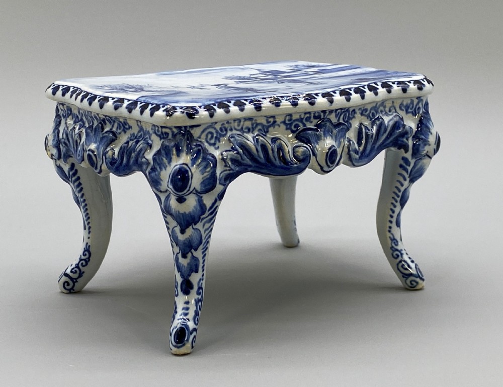 A four-piece set of miniature ceramic furniture decorated with hand-painted blue and white Dutch landscapes and windmill scenes. View X