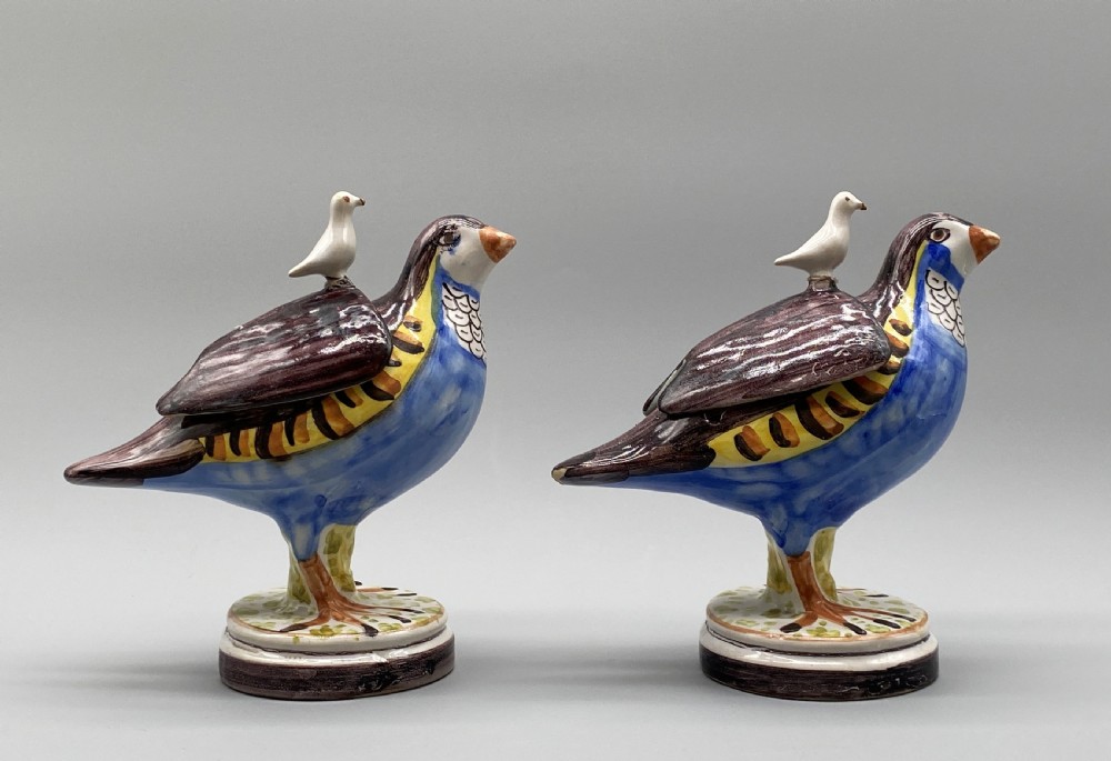 A pair of 18th-century Spanish tin-glazed faience tureens fashioned as partridges with hand-painted blue, yellow, and brown plumage and small bird finials on their removable covers. View V