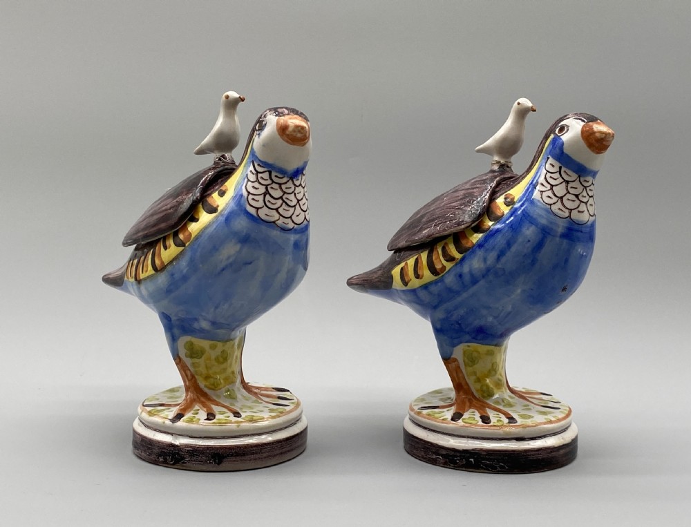 A pair of 18th-century Spanish tin-glazed faience tureens fashioned as partridges with hand-painted blue, yellow, and brown plumage and small bird finials on their removable covers. View VI