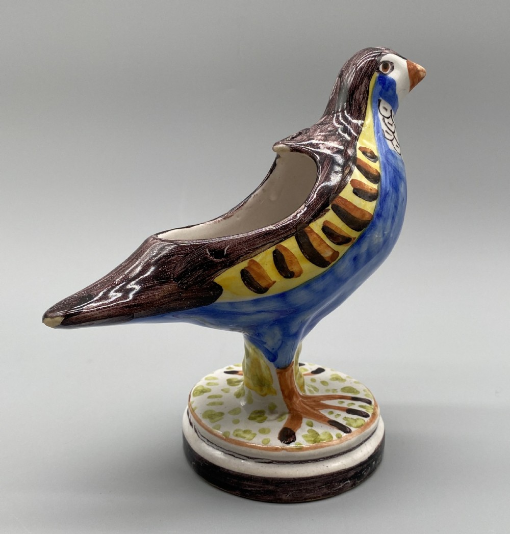 A pair of 18th-century Spanish tin-glazed faience tureens fashioned as partridges with hand-painted blue, yellow, and brown plumage and small bird finials on their removable covers. View XVII
