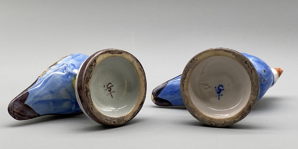 A pair of 18th-century Spanish tin-glazed faience tureens fashioned as partridges with hand-painted blue, yellow, and brown plumage and small bird finials on their removable covers. View XVIII