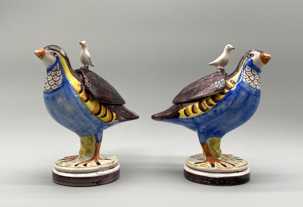 A pair of 18th-century Spanish tin-glazed faience tureens fashioned as partridges with hand-painted blue, yellow, and brown plumage and small bird finials on their removable covers. View XXII