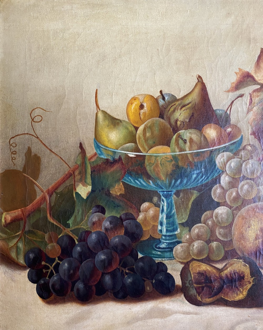 An oil painting depicting a still life composition of grapes, pears, peaches, and figs arranged on a draped cloth with a blue glass pedestal dish, enclosed in a moulded gilt frame. View V