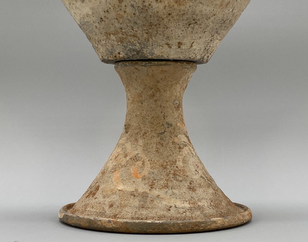 A painted terracotta vessel from the Tang Dynasty featuring a bulbous body, pointed finial lid, flared pedestal foot, and painted geometric scroll motifs in red and grey pigments. View VI