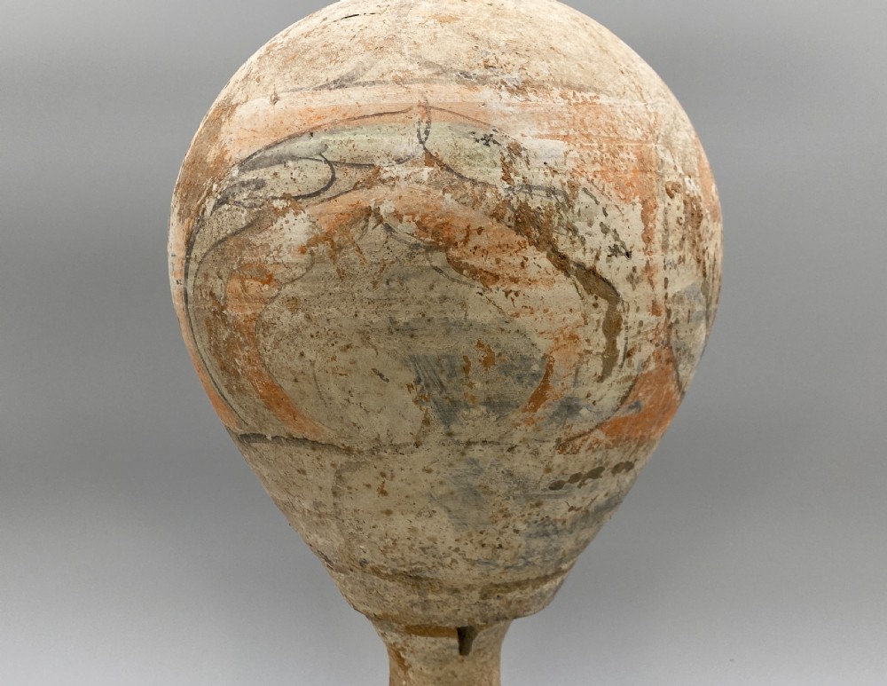 A painted terracotta vessel from the Tang Dynasty featuring a bulbous body, pointed finial lid, flared pedestal foot, and painted geometric scroll motifs in red and grey pigments. View VIII