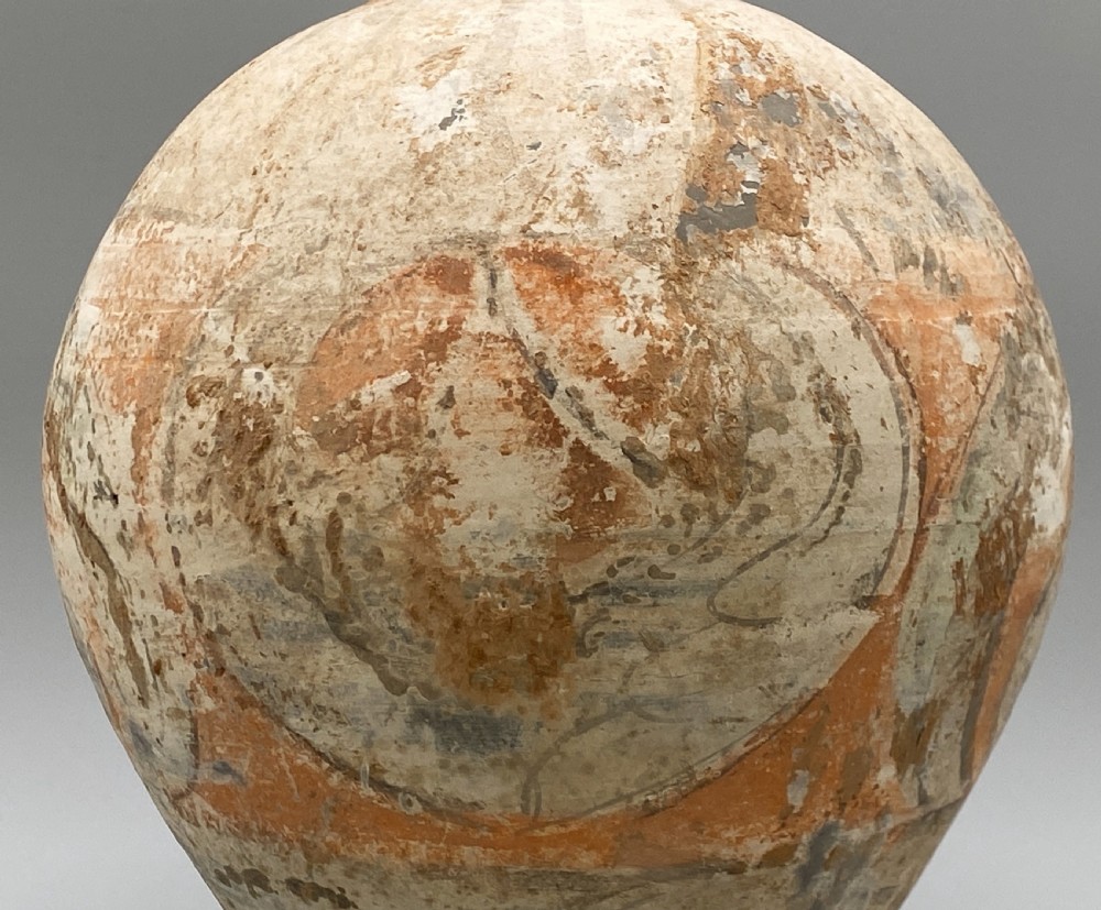 A painted terracotta vessel from the Tang Dynasty featuring a bulbous body, pointed finial lid, flared pedestal foot, and painted geometric scroll motifs in red and grey pigments. View XV