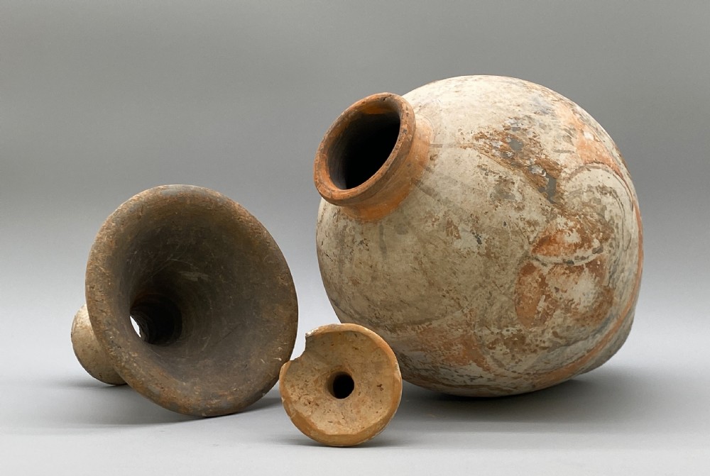 A painted terracotta vessel from the Tang Dynasty featuring a bulbous body, pointed finial lid, flared pedestal foot, and painted geometric scroll motifs in red and grey pigments. View XVI
