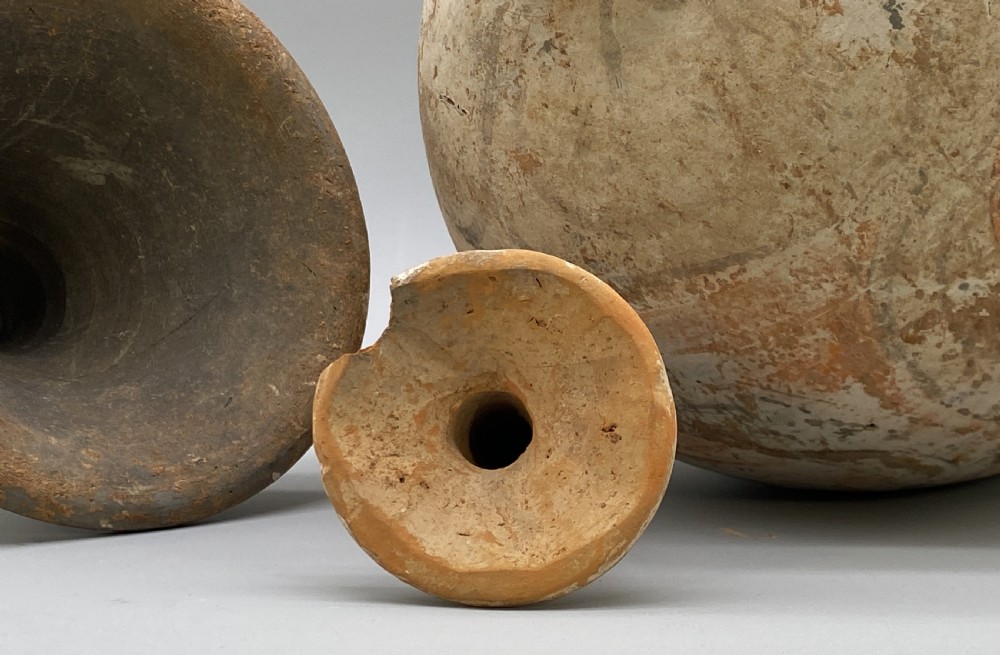 A painted terracotta vessel from the Tang Dynasty featuring a bulbous body, pointed finial lid, flared pedestal foot, and painted geometric scroll motifs in red and grey pigments. View XVIII