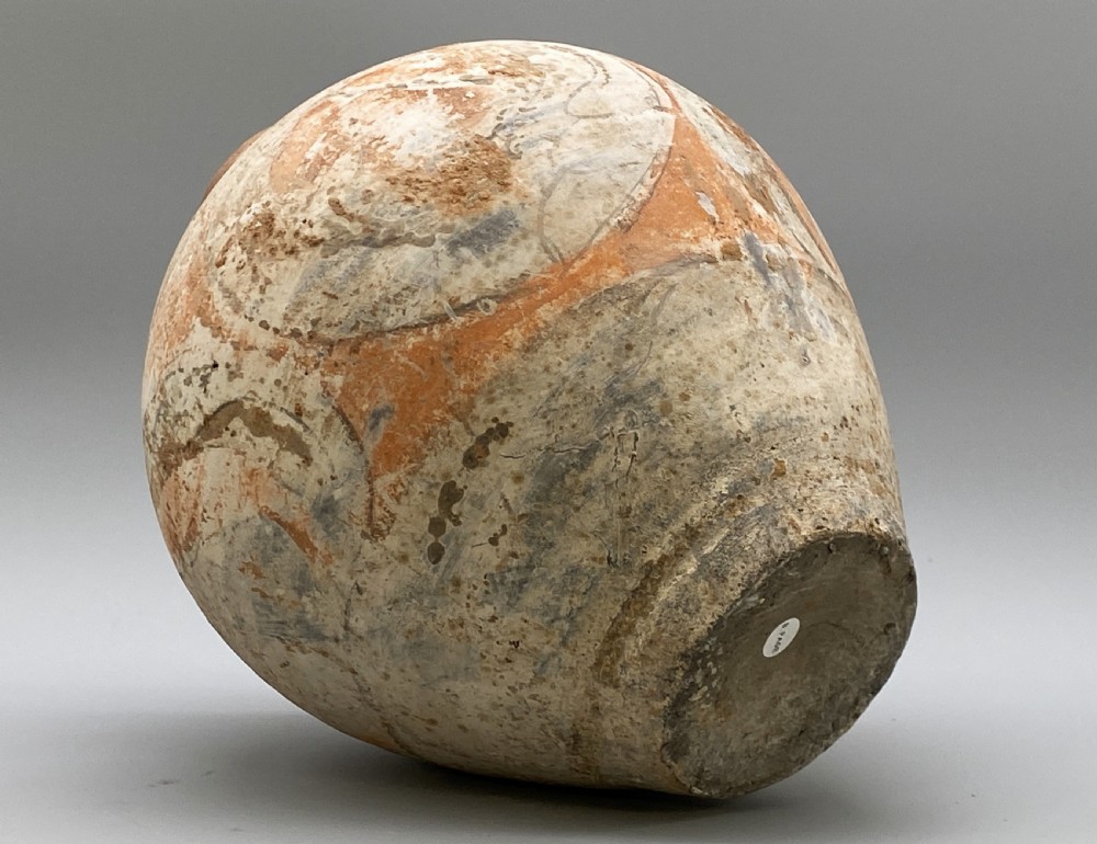 A painted terracotta vessel from the Tang Dynasty featuring a bulbous body, pointed finial lid, flared pedestal foot, and painted geometric scroll motifs in red and grey pigments. View XX