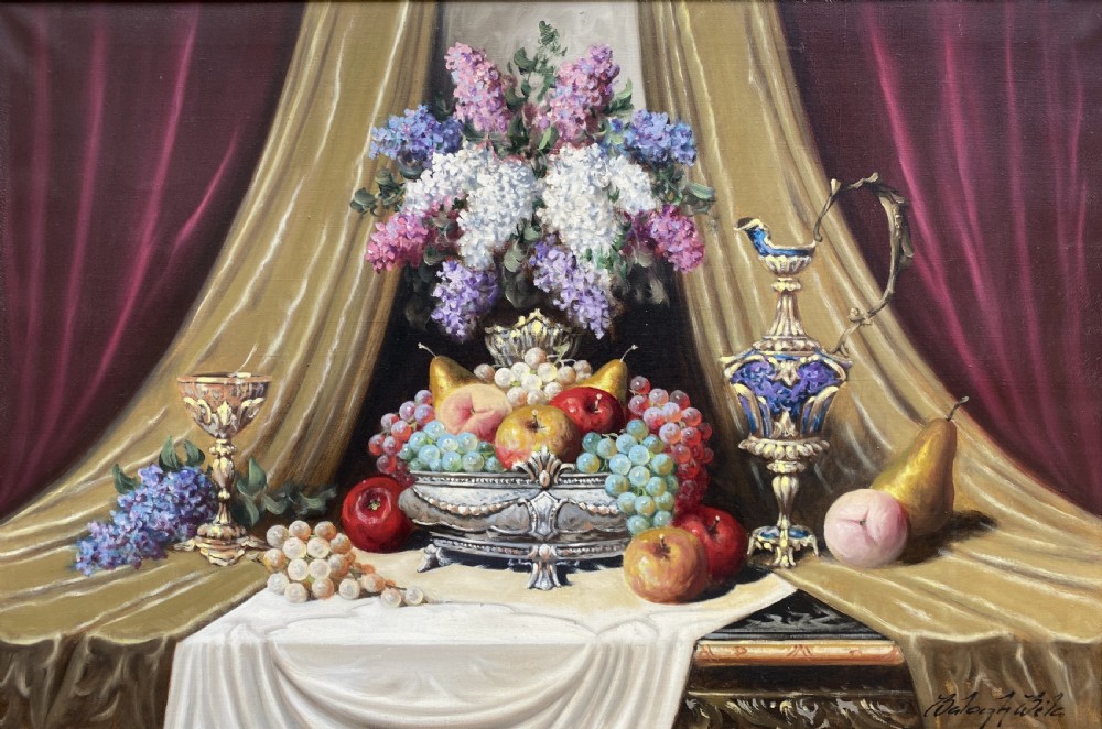 A framed oil painting on canvas depicting a table with fruit, lilacs in a central vase, silver ewers, and draped gold and burgundy fabrics. View II