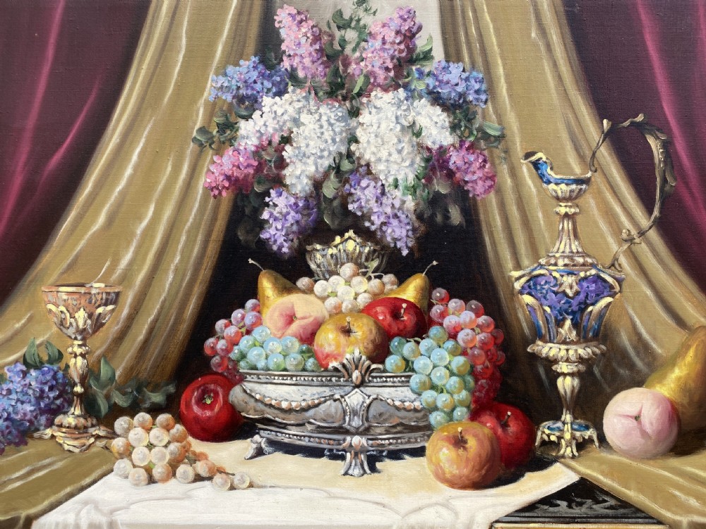 A framed oil painting on canvas depicting a table with fruit, lilacs in a central vase, silver ewers, and draped gold and burgundy fabrics. View III