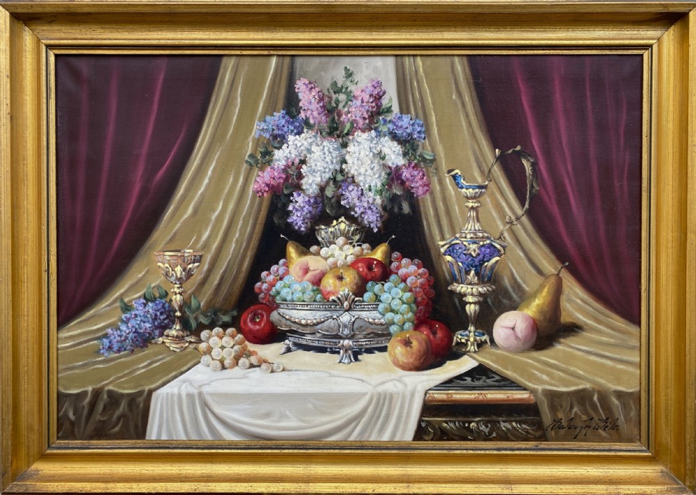 A framed oil painting on canvas depicting a table with fruit, lilacs in a central vase, silver ewers, and draped gold and burgundy fabrics. View XI