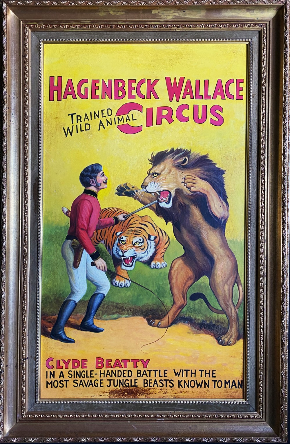 A framed mid-twentieth-century oil painting depicting a lion tamer confronting a roaring lion and a tiger against a yellow background with bold red circus lettering.