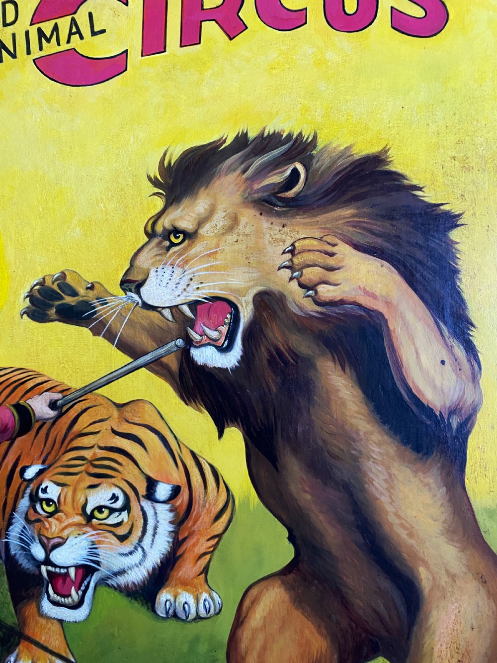 A framed mid-twentieth-century oil painting depicting a lion tamer confronting a roaring lion and a tiger against a yellow background with bold red circus lettering. View VII