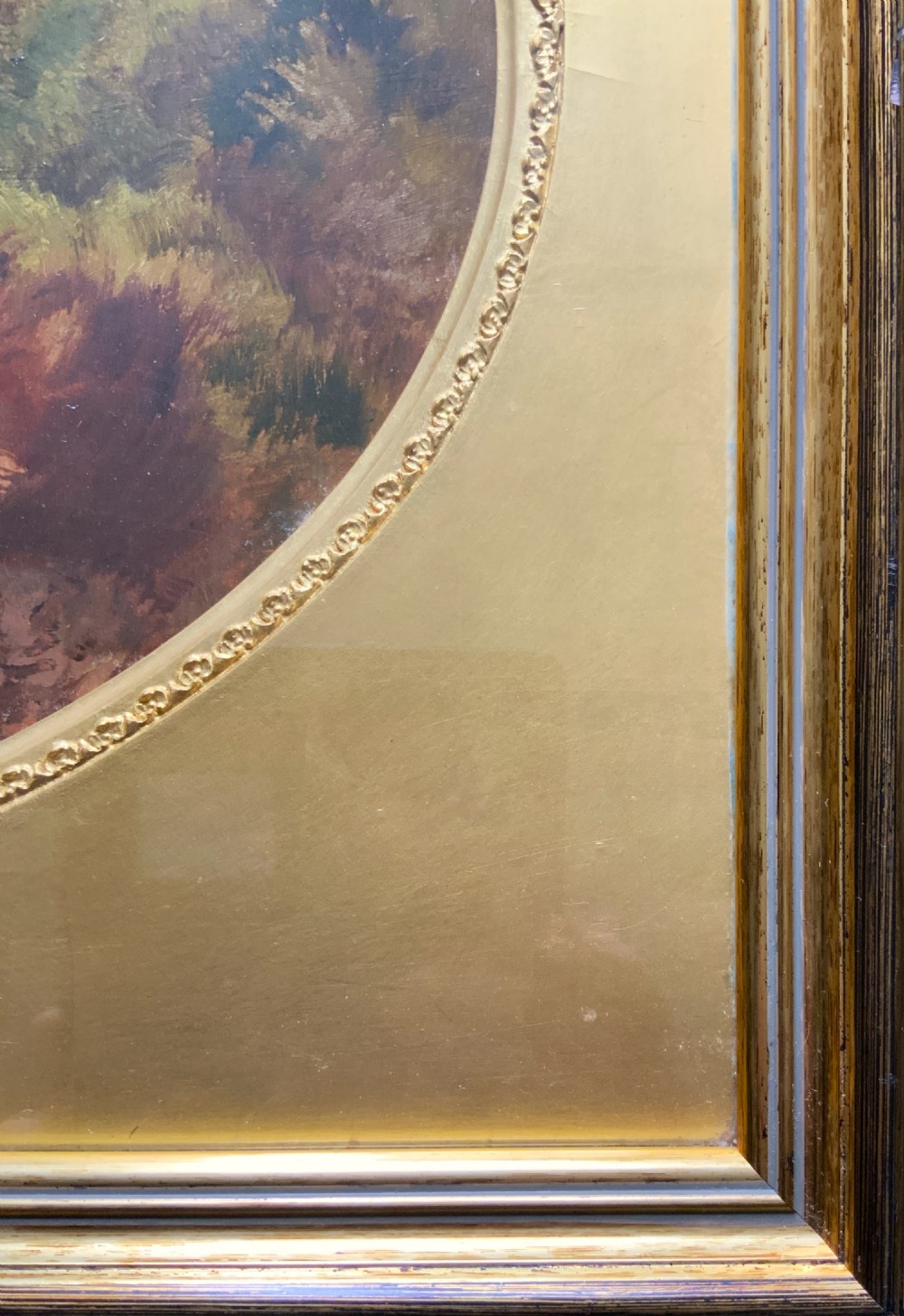 An oval 19th-century oil landscape painting depicting a wooded bank and open fields, set inside a rectangular gilded frame. View VIII
