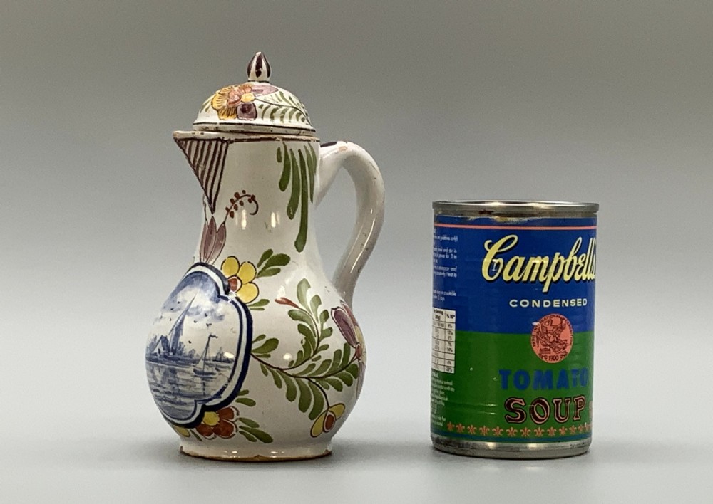 An 18th-century Dutch Delft tin-glazed ceramic coffee pot decorated with polychrome floral motifs and a central blue maritime landscape medallion. View II