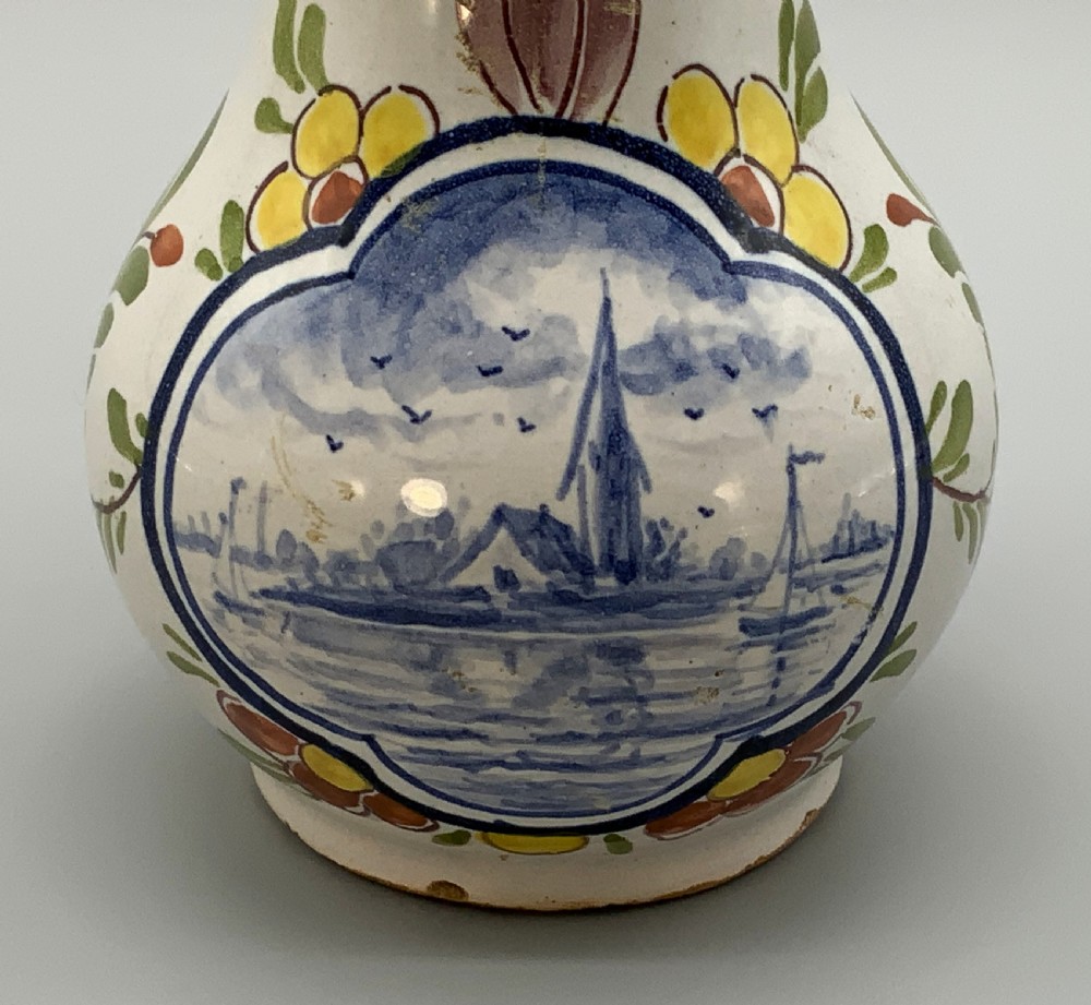An 18th-century Dutch Delft tin-glazed ceramic coffee pot decorated with polychrome floral motifs and a central blue maritime landscape medallion. View IX
