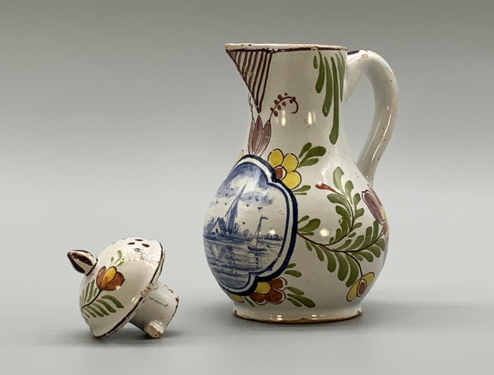 An 18th-century Dutch Delft tin-glazed ceramic coffee pot decorated with polychrome floral motifs and a central blue maritime landscape medallion. View X