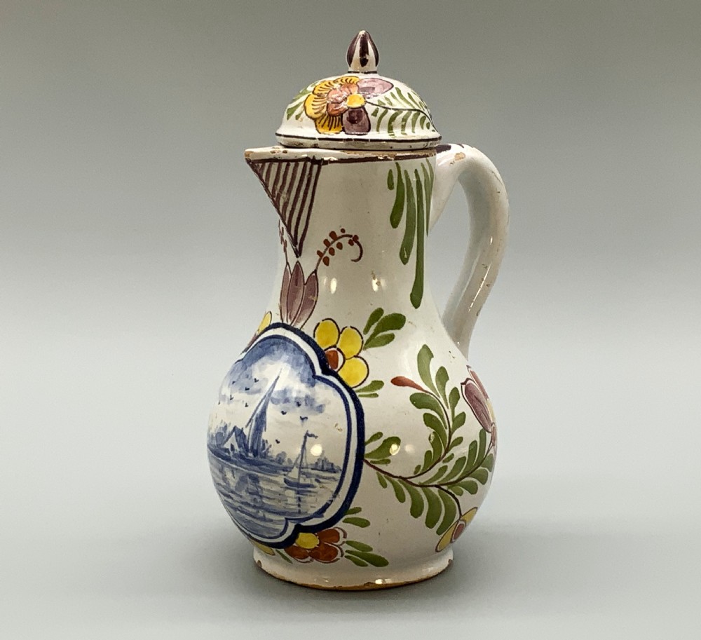 An 18th-century Dutch Delft tin-glazed ceramic coffee pot decorated with polychrome floral motifs and a central blue maritime landscape medallion. View XVI