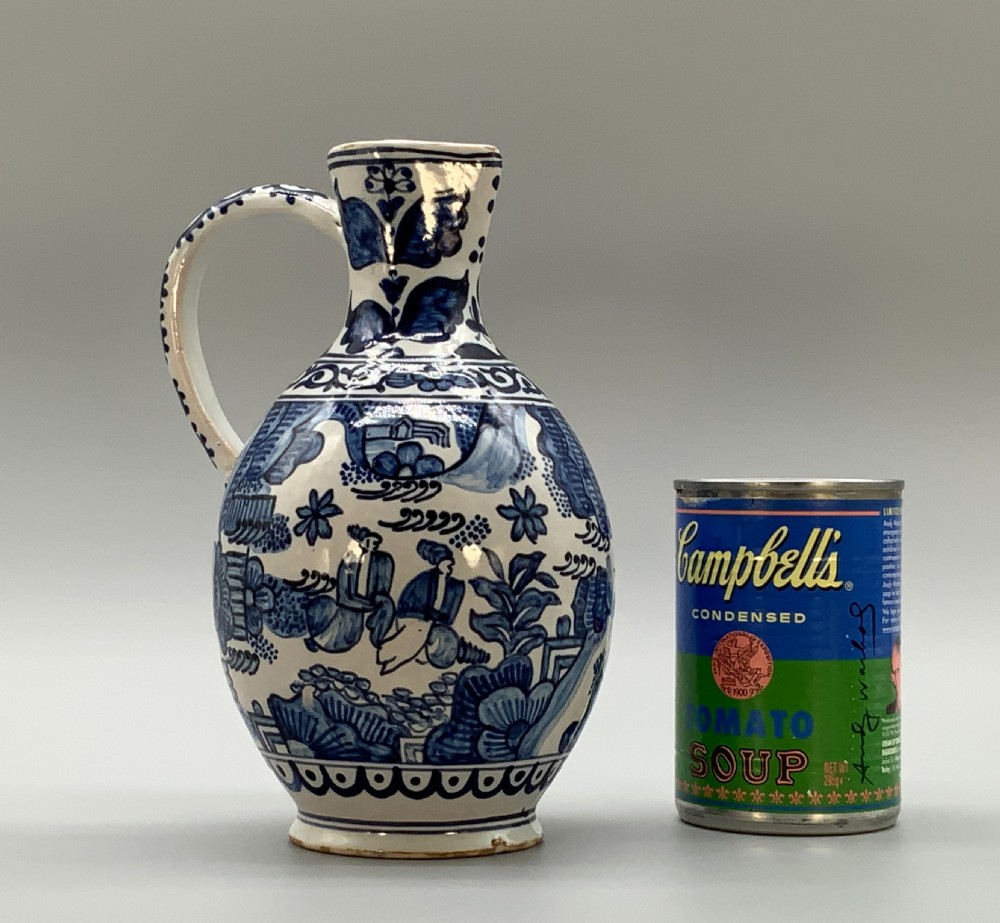 An antique Dutch Delftware ceramic jug decorated with cobalt blue hand-painted Chinoiserie figures and botanical motifs against a white tin glaze. View II