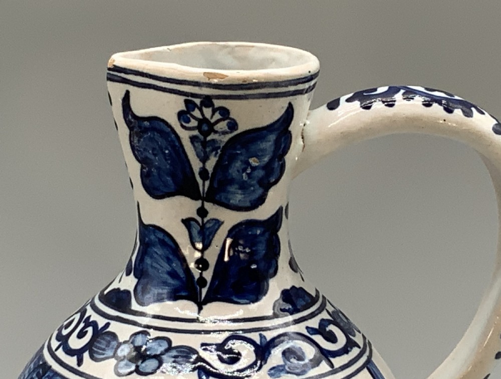 An antique Dutch Delftware ceramic jug decorated with cobalt blue hand-painted Chinoiserie figures and botanical motifs against a white tin glaze. View V