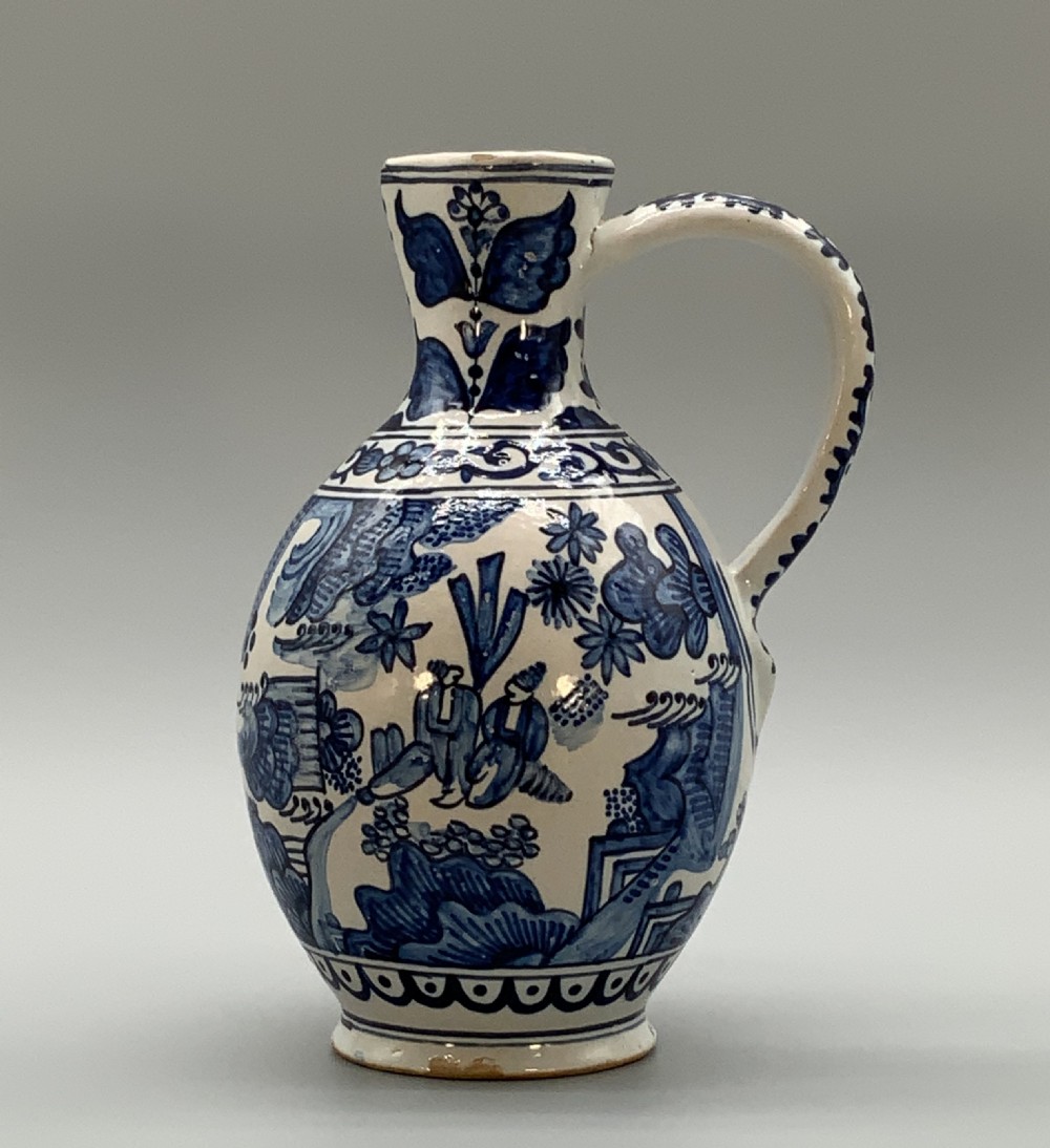 An antique Dutch Delftware ceramic jug decorated with cobalt blue hand-painted Chinoiserie figures and botanical motifs against a white tin glaze. View VI