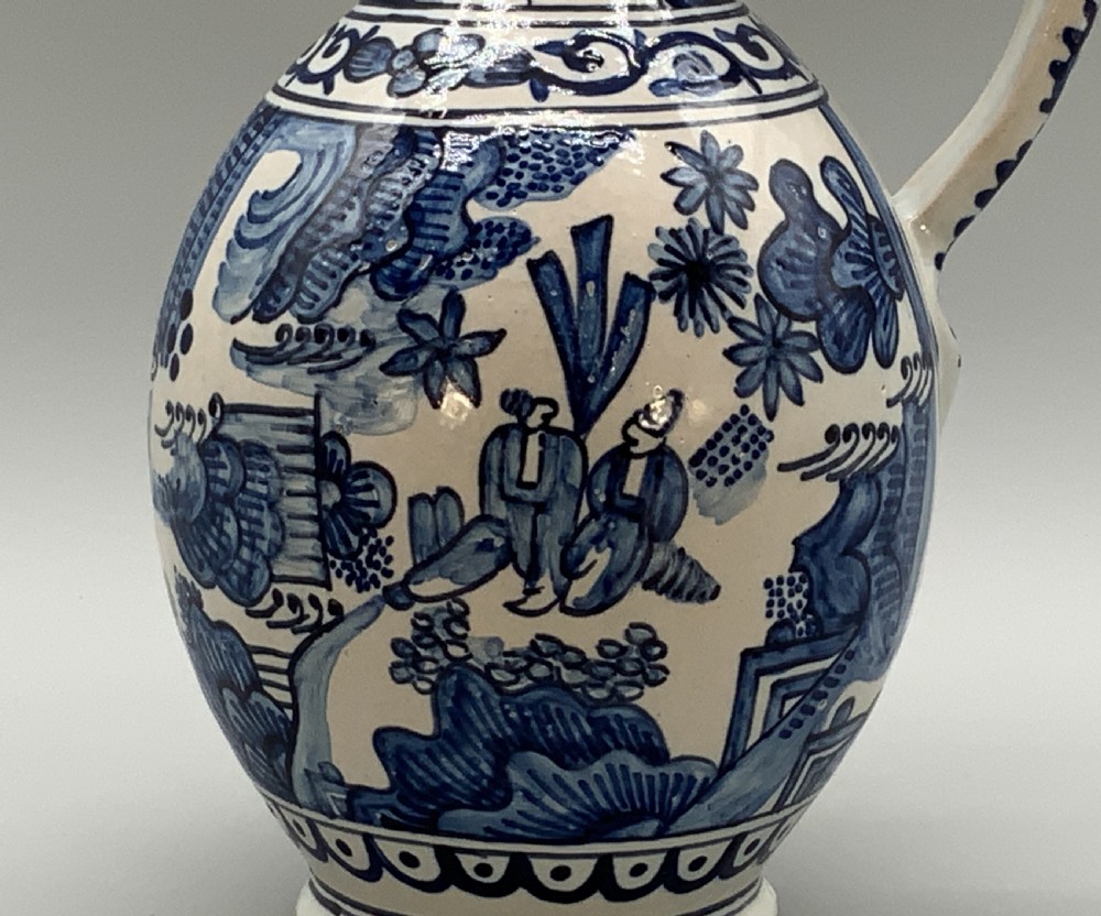 An antique Dutch Delftware ceramic jug decorated with cobalt blue hand-painted Chinoiserie figures and botanical motifs against a white tin glaze. View VIII