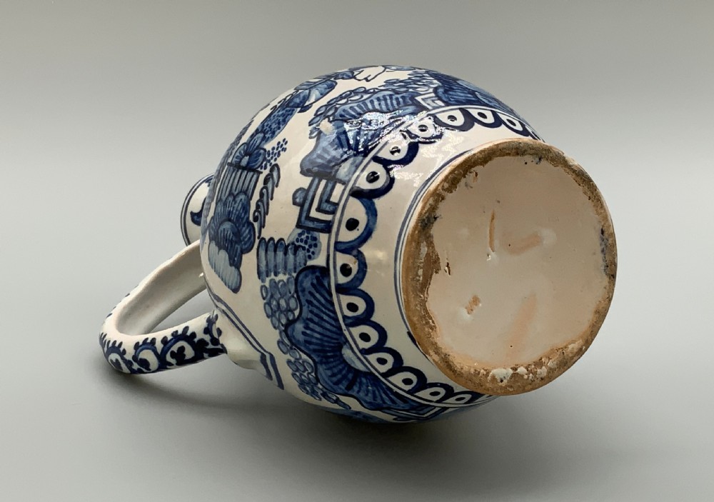An antique Dutch Delftware ceramic jug decorated with cobalt blue hand-painted Chinoiserie figures and botanical motifs against a white tin glaze. View XIV