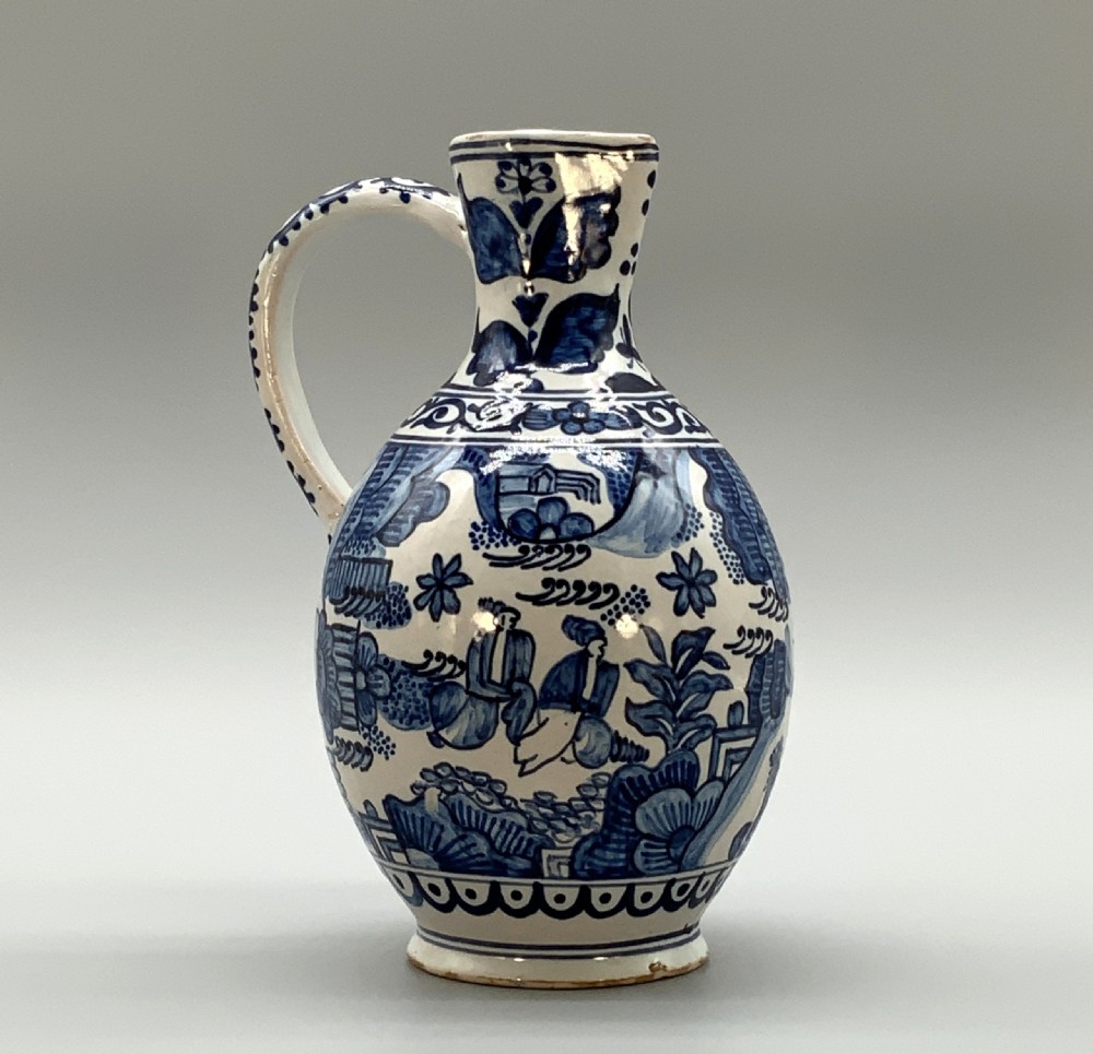 An antique Dutch Delftware ceramic jug decorated with cobalt blue hand-painted Chinoiserie figures and botanical motifs against a white tin glaze. View XVI