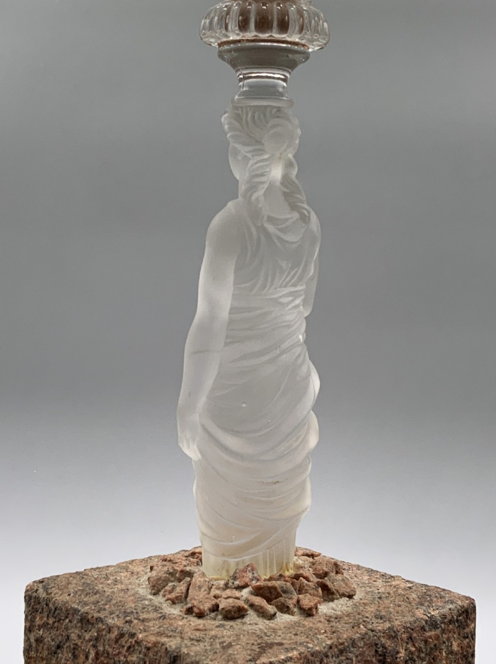 An early 20th-century French table lamp featuring a frosted glass classical figurine mounted on a square stone base, topped with a pleated blue floral lampshade. View XIII