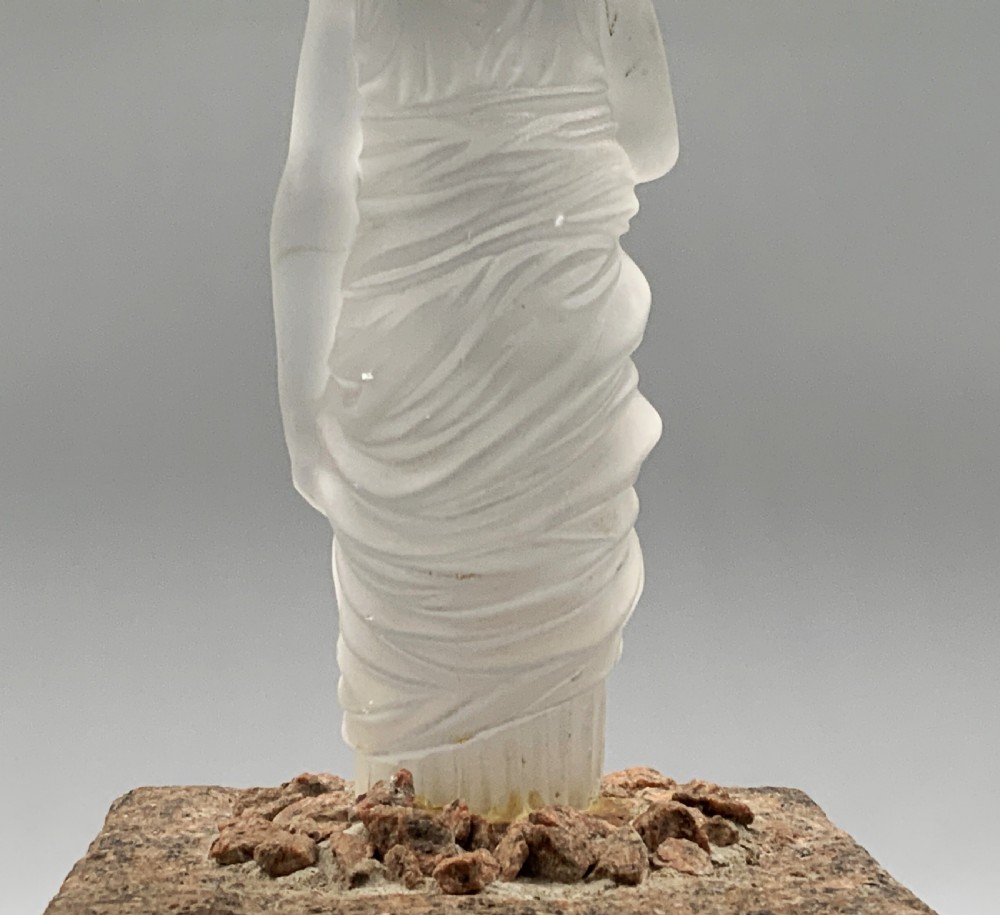 An early 20th-century French table lamp featuring a frosted glass classical figurine mounted on a square stone base, topped with a pleated blue floral lampshade. View XV