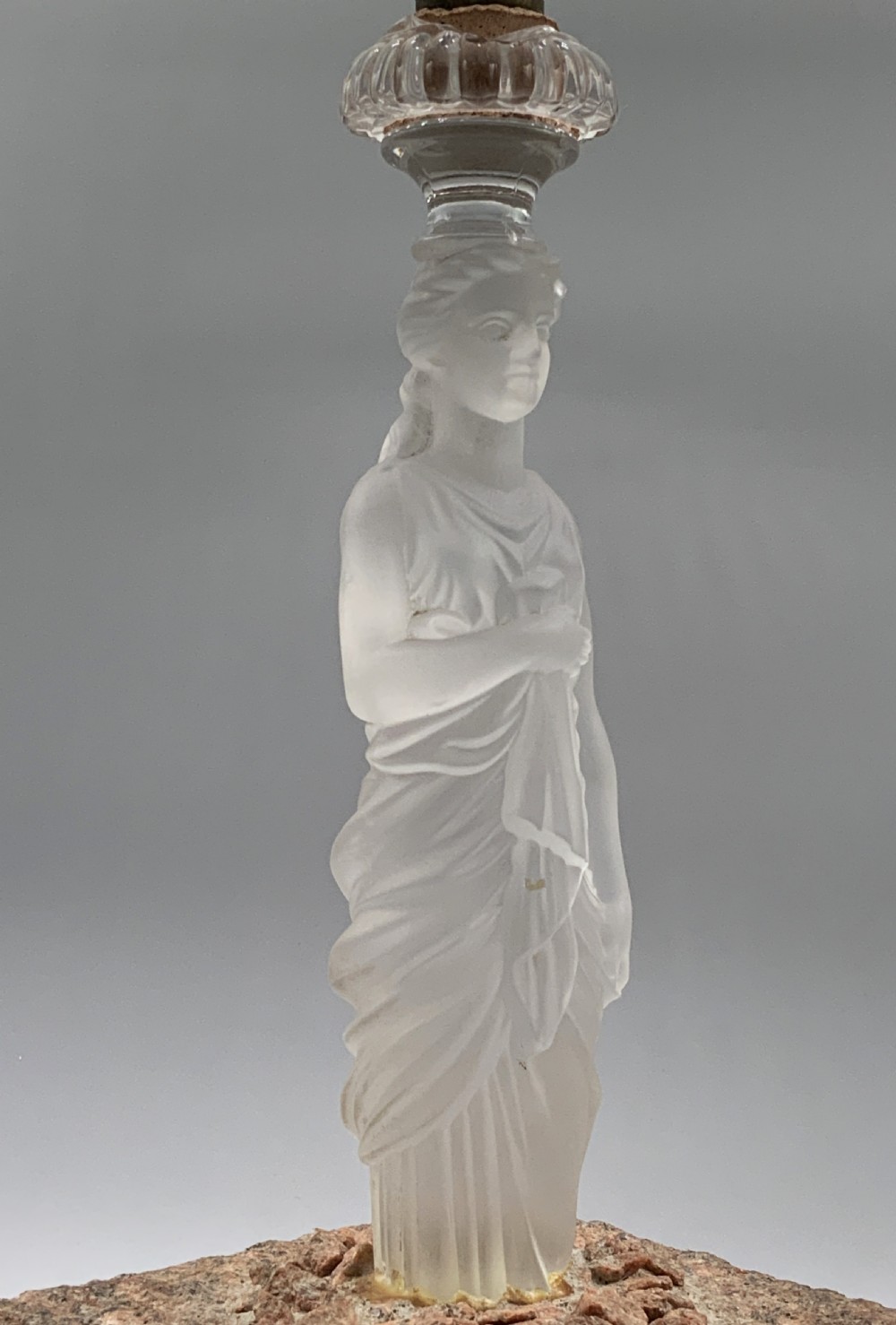 An early 20th-century French table lamp featuring a frosted glass classical figurine mounted on a square stone base, topped with a pleated blue floral lampshade. View XVIII