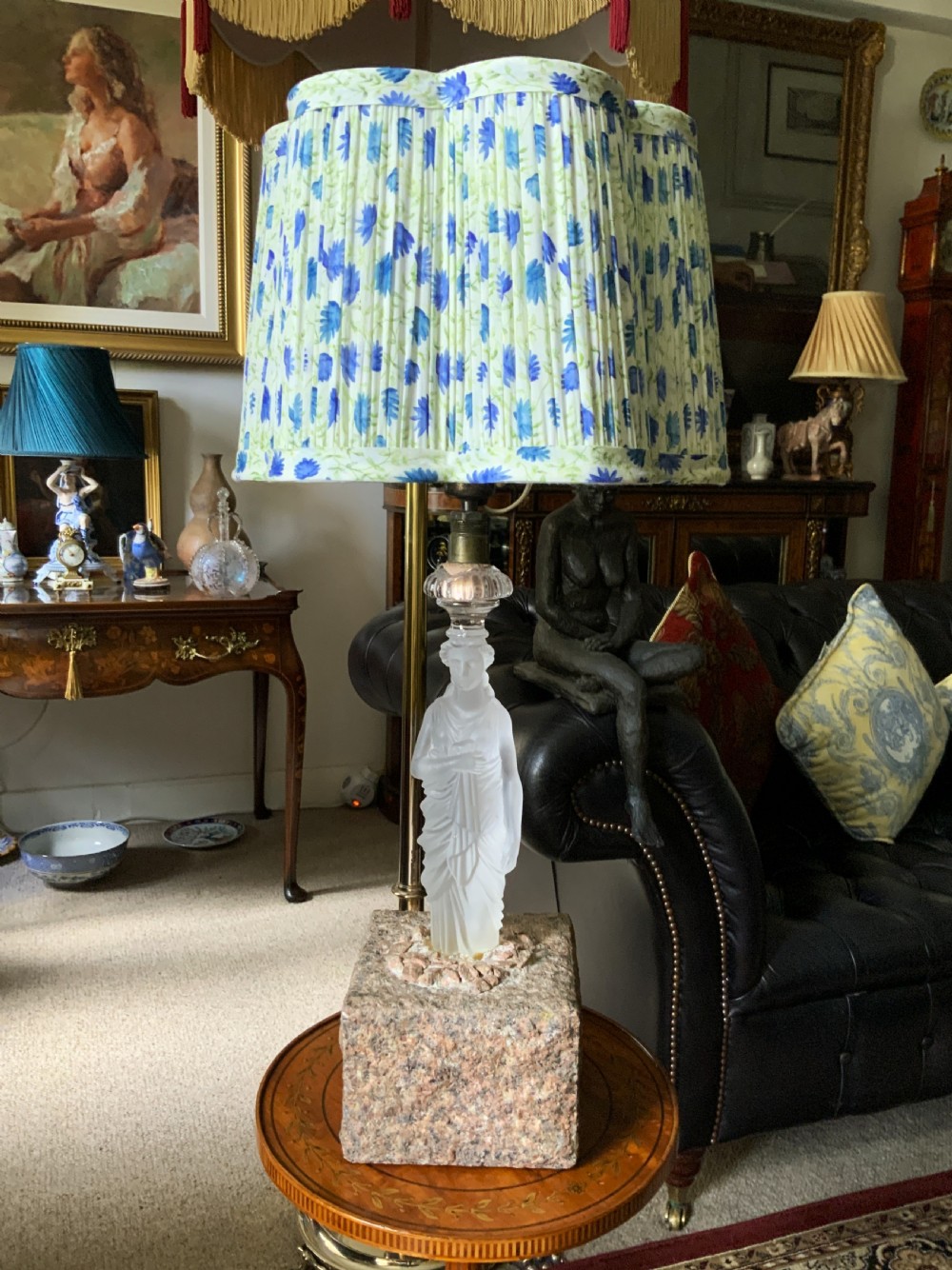An early 20th-century French table lamp featuring a frosted glass classical figurine mounted on a square stone base, topped with a pleated blue floral lampshade. View XXI