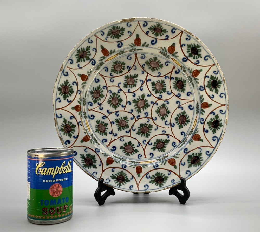 An 18th-century circular Dutch Delftware ceramic charger plate featuring hand-painted green, brown, and blue geometric floral lattice patterns on an off-white tin glaze. View II