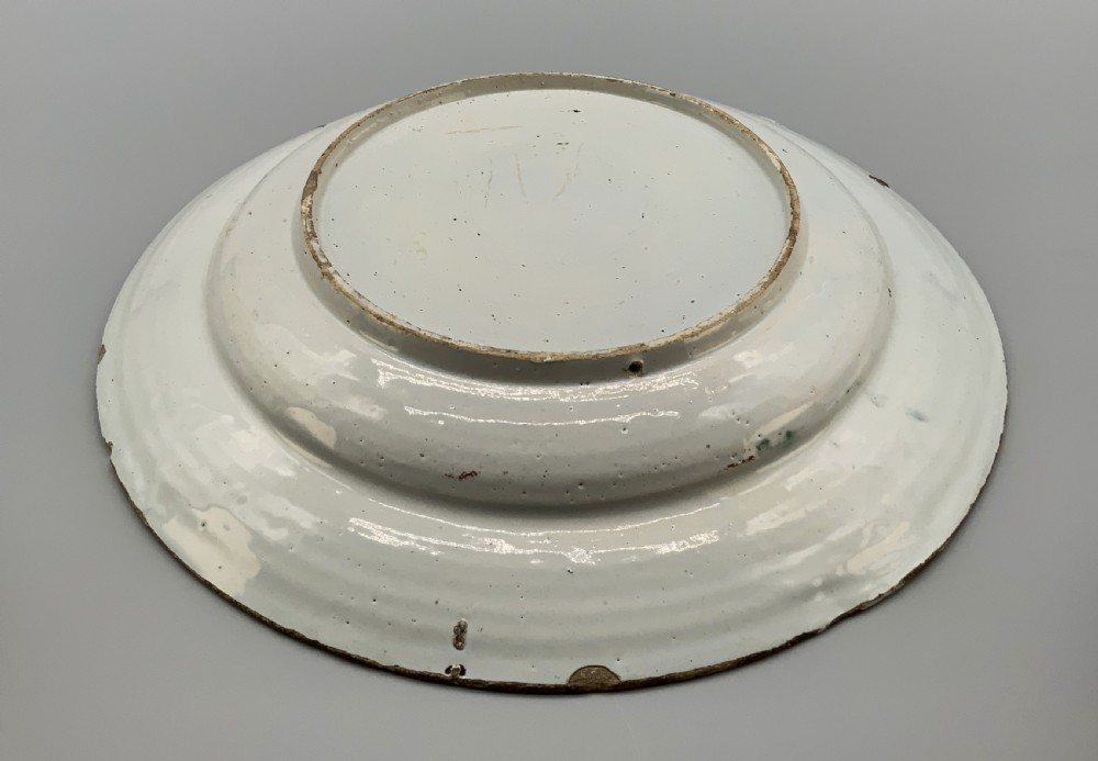 An 18th-century circular Dutch Delftware ceramic charger plate featuring hand-painted green, brown, and blue geometric floral lattice patterns on an off-white tin glaze. View XIII