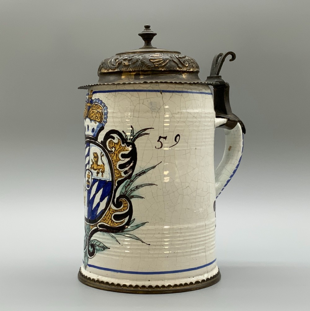 A 19th-century cream tin-glazed earthenware beer stein decorated with a hand-painted coat of arms and fitted with an embossed pewter lid. View III