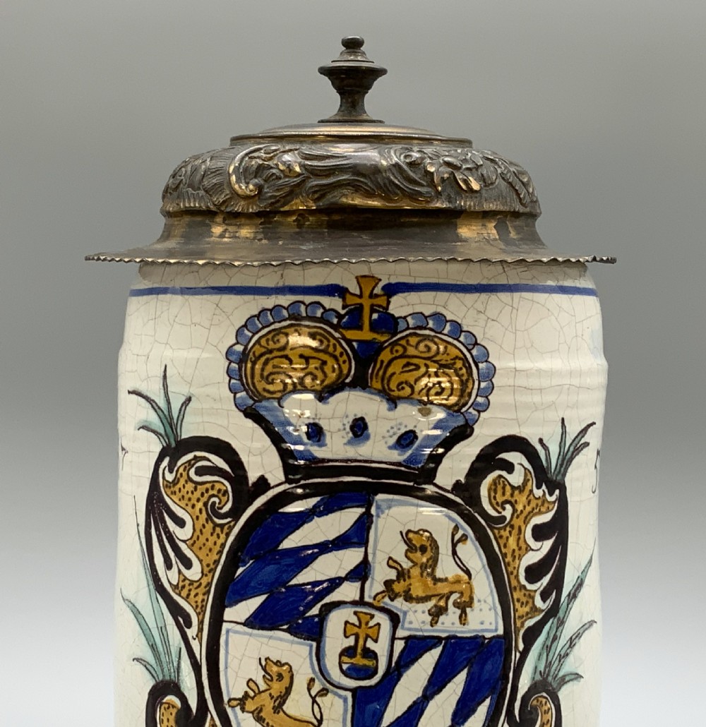 A 19th-century cream tin-glazed earthenware beer stein decorated with a hand-painted coat of arms and fitted with an embossed pewter lid. View VIII
