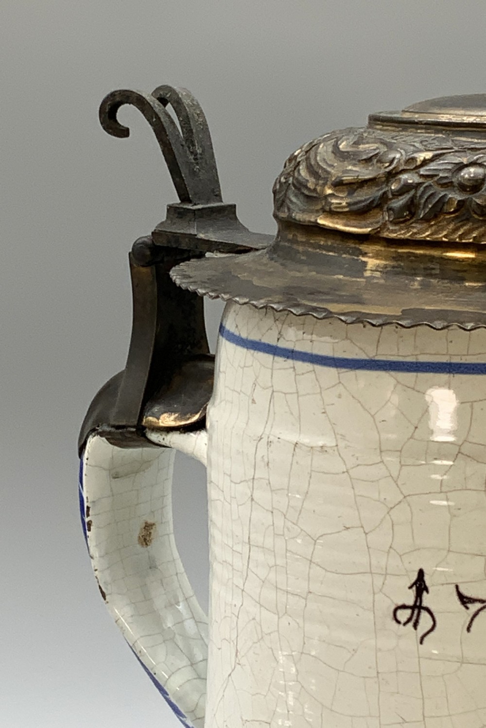 A 19th-century cream tin-glazed earthenware beer stein decorated with a hand-painted coat of arms and fitted with an embossed pewter lid. View X