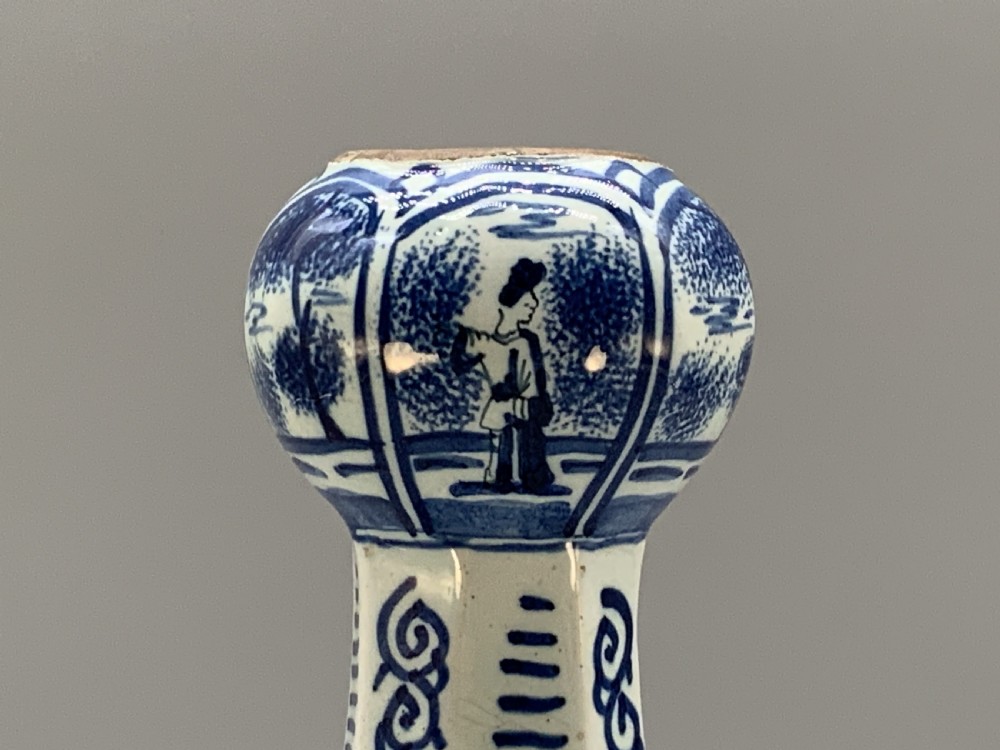 A tall, octagonal blue and white tin-glazed earthenware vase featuring a garlic bulb neck and hand-painted Chinoiserie scenes within arched panels. View VII